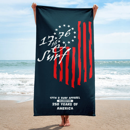 Person holding up the navy 1776 & Surf beach towel on the sand, featuring the 1776 script logo, 13-star Betsy Ross flag, and 'Celebrating 250 Years of America' graphic – America's 250th Anniversary Collection by 17th & Surf