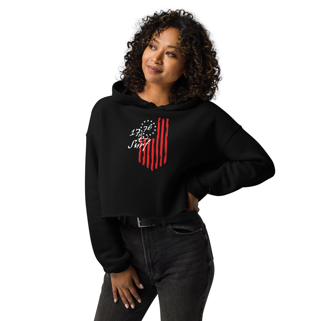 Woman wearing the black "1776 & Surf" crop hoodie, front view, featuring the large 1776 script logo with 13-star Betsy Ross flag and distressed red stripe graphic centered on the chest – America's 250th Anniversary Collection by 17th & Surf