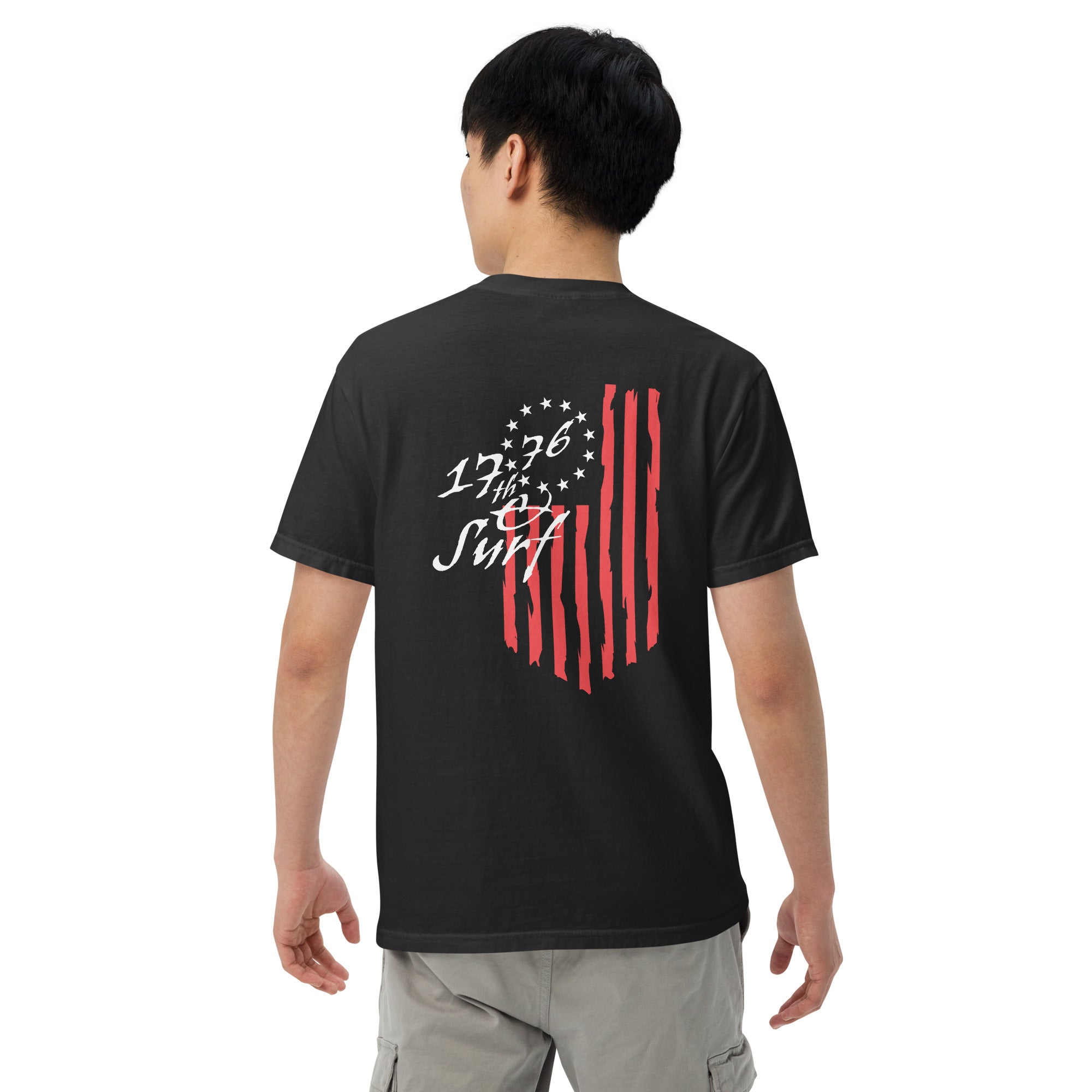Man wearing the black "1776 & Surf" tee, back view, featuring the large 1776 script logo with 13-star Betsy Ross flag and distressed red stripe graphic – America's 250th Anniversary Collection by 17th & Surf