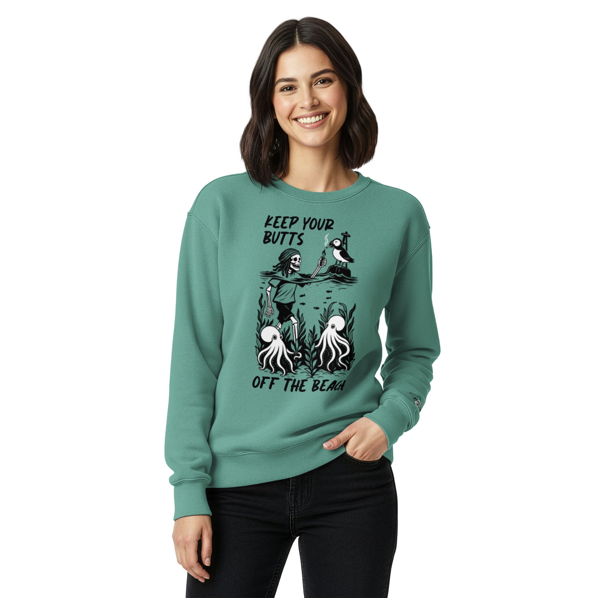 "Keep Your Butts Off The Beach" heavyweight crewneck sweatshirt front view in seafoam on model featuring skeleton lighting a cigarette for a puffin with octopuses in seaweed graphic and small sleeve logo - 17th & Surf