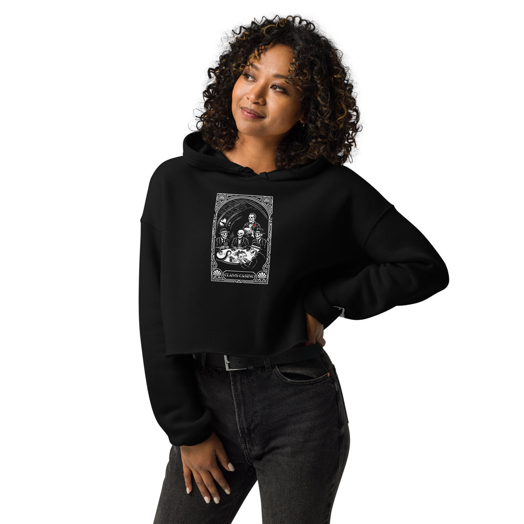 Woman wearing the "Clam's Casino" cropped hoodie in black, front view, featuring the large art nouveau "CLAMS CASINO" poker scene with skeleton mobsters, a tuxedo-clad Don holding a catfish, and an octopus tentacle reaching across the table – Clam's Casino Series by 17th & Surf