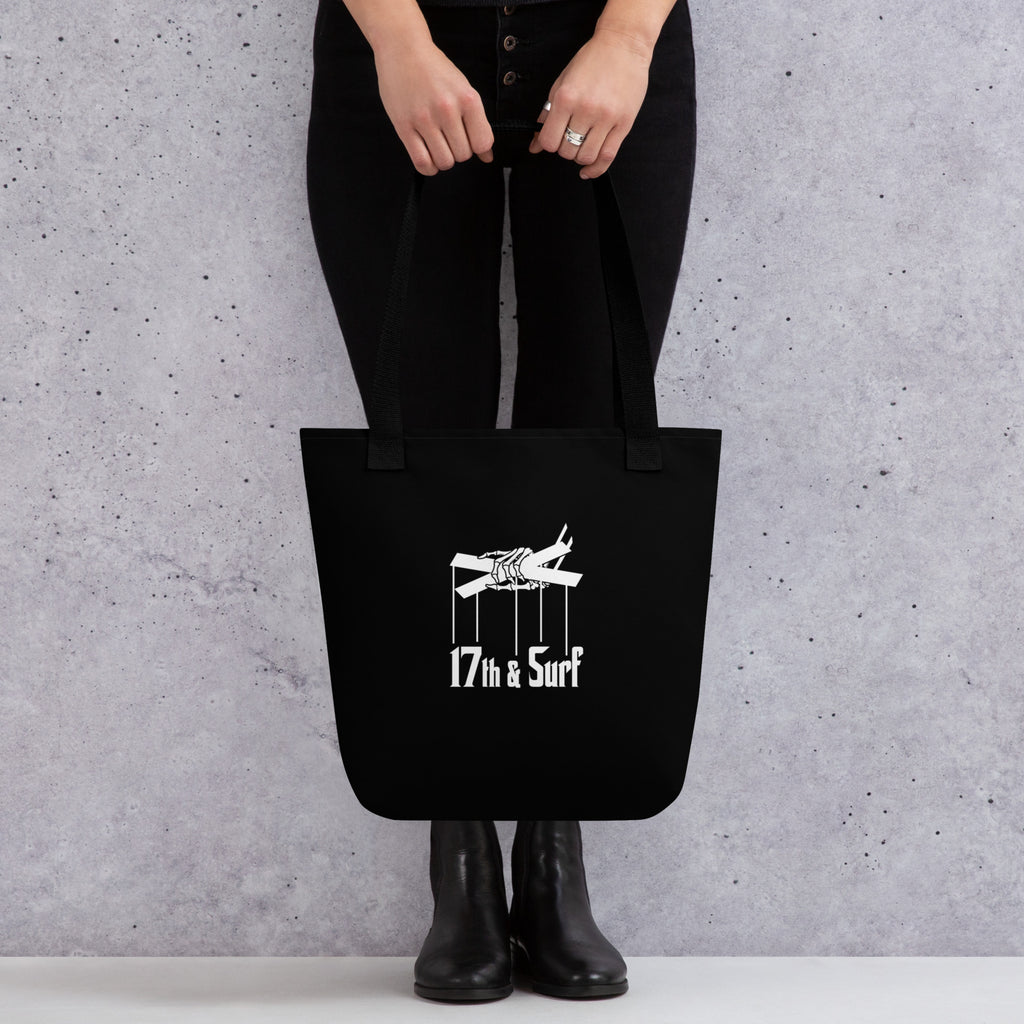 Woman holding the "Clams Casino" black canvas tote bag, back view, featuring the small "17th & Surf" skeletal puppeteer-hand logo – Clam's Casino Series by 17th & Surf