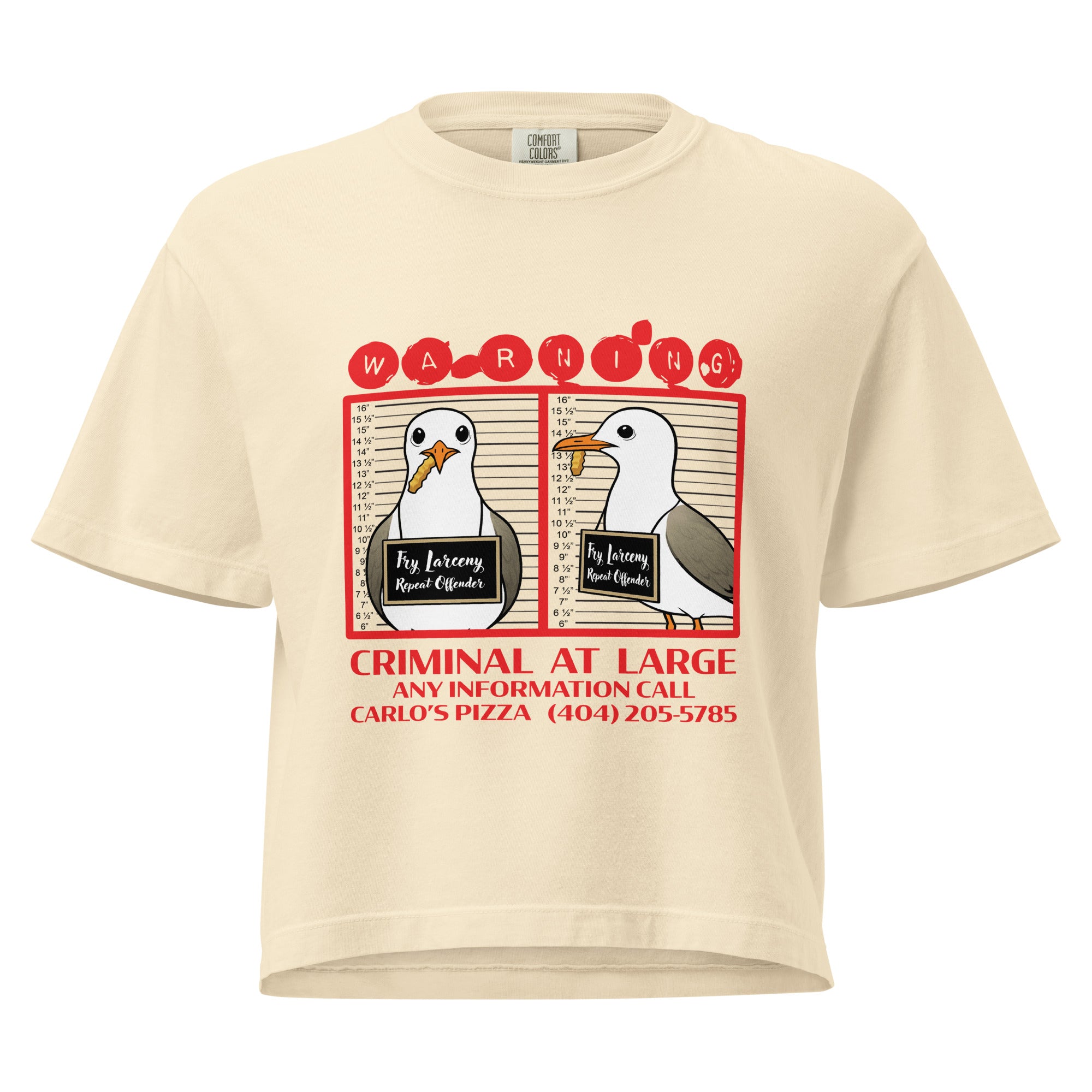 "Criminal At Large" ivory women's heavyweight boxy tee, front flat lay, featuring seagull "WARNING" mugshot graphic with "Fry Larceny, Repeat Offender" police lineup – 17th & Surf x Carlo's Pizza