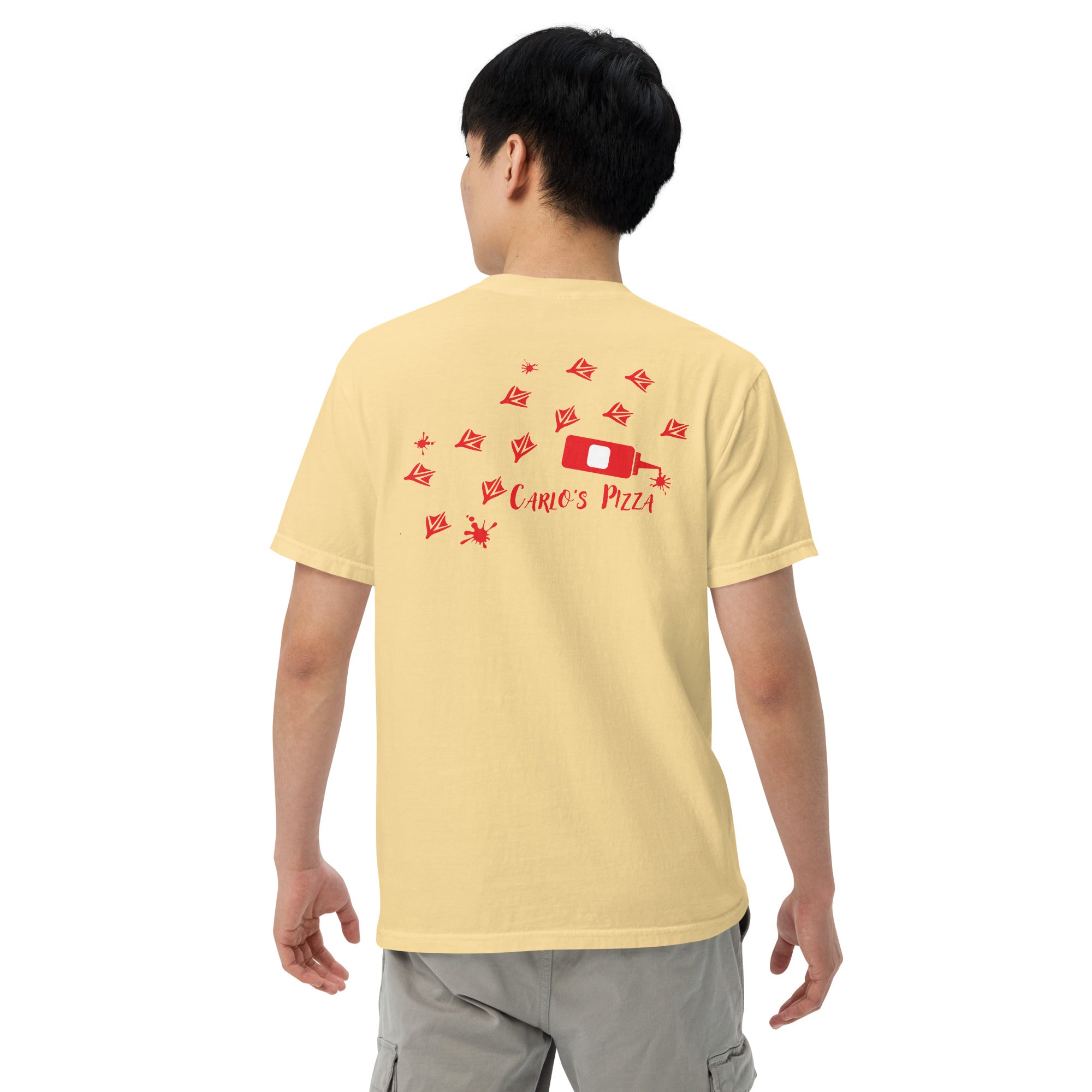 "Criminal At Large" pale yellow garment-dyed heavyweight tee on male model, back view, featuring red seagull footprint trail and Carlo's Pizza ketchup bottle design – 17th & Surf x Carlo's Pizza
