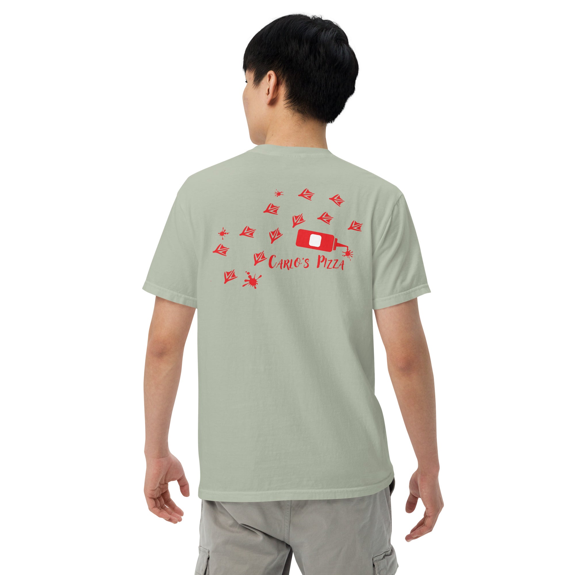 "Criminal At Large" sage green garment-dyed heavyweight tee on male model, back view, featuring red seagull footprint trail and Carlo's Pizza ketchup bottle design – 17th & Surf x Carlo's Pizza