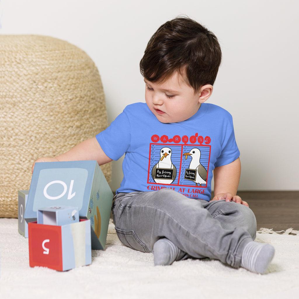 "Criminal At Large" columbia blue toddler tee on toddler model, front view, featuring seagull "WARNING" mugshot graphic with "Fry Larceny, Repeat Offender" police lineup – 17th & Surf x Carlo's Pizza