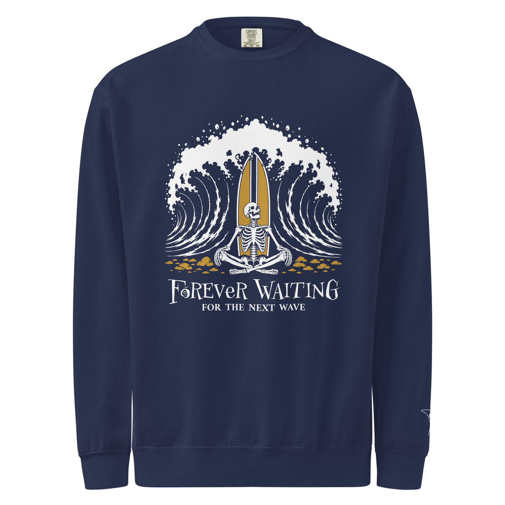 "Forever Waiting For The Next Wave" crewneck sweatshirt, True Navy, front view, featuring a meditating skeleton surfer, board planted upright behind him, sitting cross-legged on the shore as breakers roll in on either side – 17th & Surf