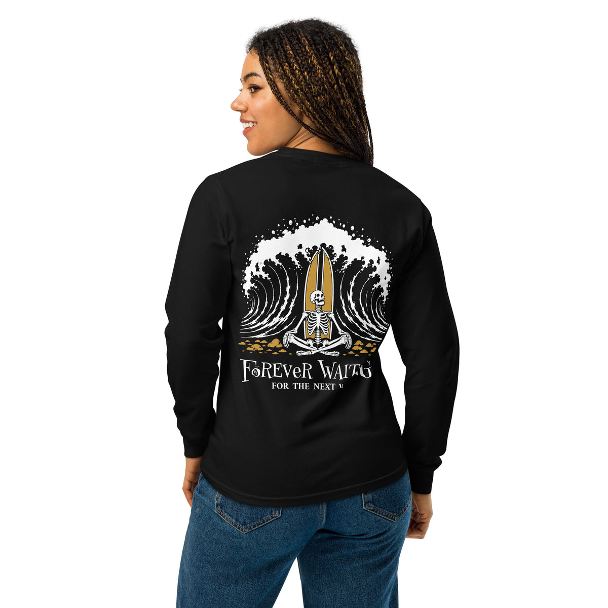 "Forever Waiting For The Next Wave" long sleeve shirt, Black, second back view, featuring a meditating skeleton surfer, board planted upright behind him, sitting cross-legged on the shore as breakers roll in on either side – 17th & Surf