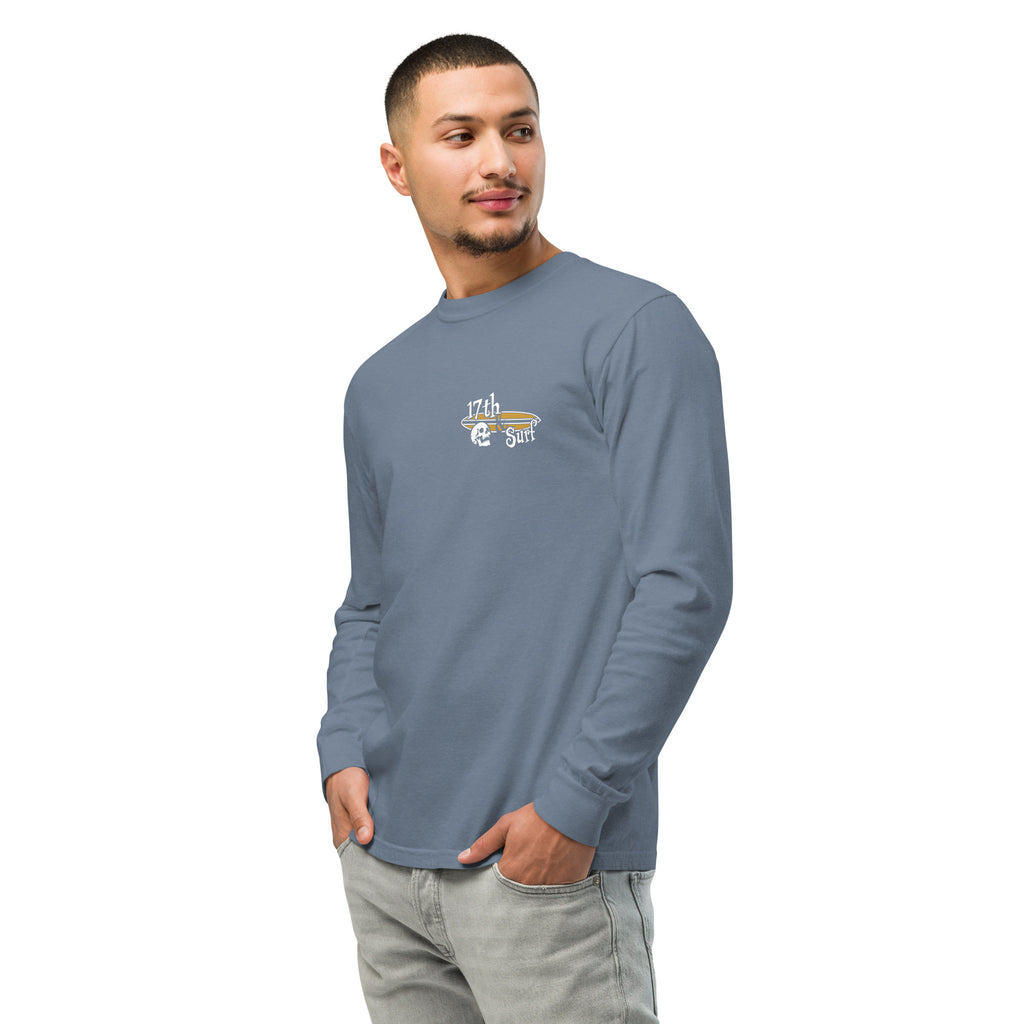 "Forever Waiting For The Next Wave" long sleeve shirt, Blue Jean, left front angle view, featuring a meditating skeleton surfer, board planted upright behind him, sitting cross-legged on the shore as breakers roll in on either side – 17th & Surf