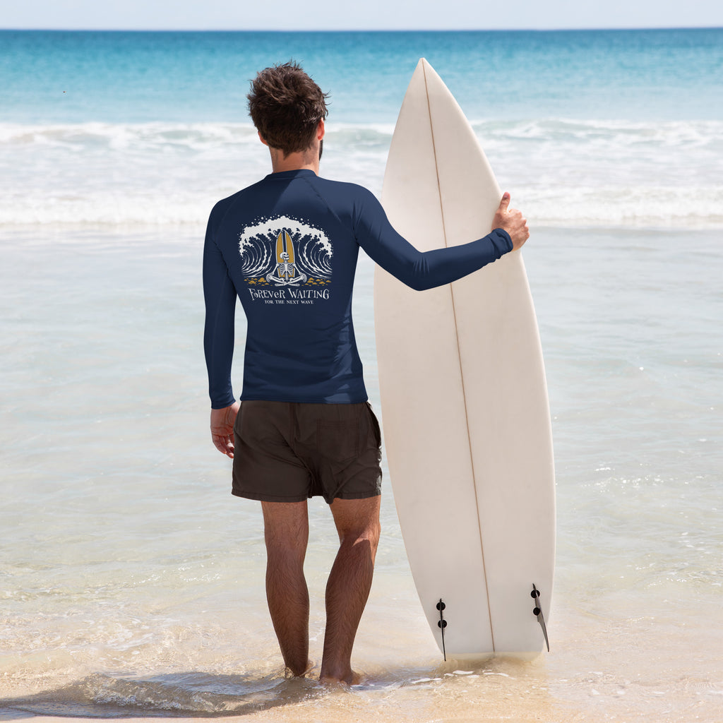 "Forever Waiting For The Next Wave" rash guard, back view, featuring a meditating skeleton surfer, board planted upright behind him, sitting cross-legged on the shore as breakers roll in on either side – 17th & Surf