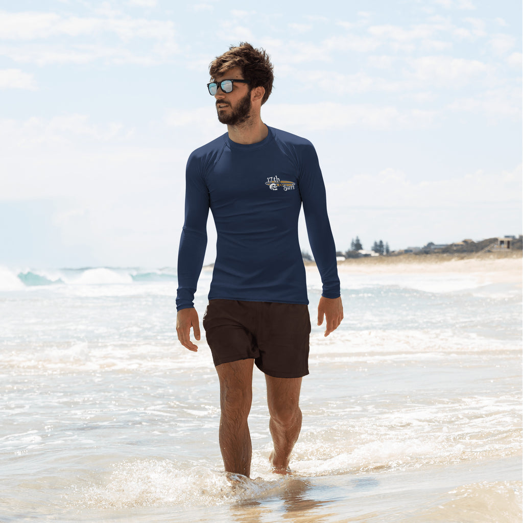 "Forever Waiting For The Next Wave" rash guard, second front view, featuring a meditating skeleton surfer, board planted upright behind him, sitting cross-legged on the shore as breakers roll in on either side – 17th & Surf