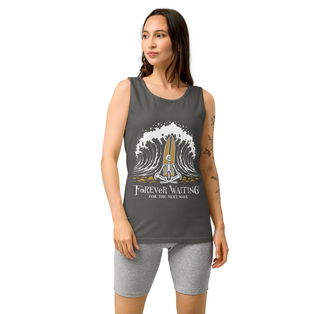 "Forever Waiting For The Next Wave" tank top, Pepper, third front view, featuring a meditating skeleton surfer, board planted upright behind him, sitting cross-legged on the shore as breakers roll in on either side – 17th & Surf