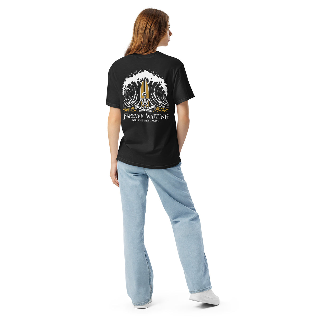 "Forever Waiting For The Next Wave" tee, Black, second back view, featuring a meditating skeleton surfer, board planted upright behind him, sitting cross-legged on the shore as breakers roll in on either side – 17th & Surf