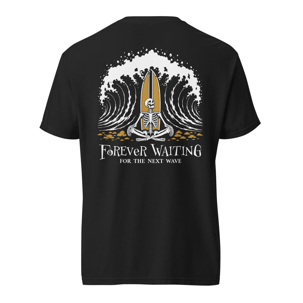 "Forever Waiting For The Next Wave" tee, Black, back view, featuring a meditating skeleton surfer, board planted upright behind him, sitting cross-legged on the shore as breakers roll in on either side – 17th & Surf
