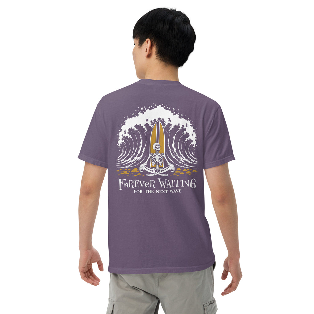 "Forever Waiting For The Next Wave" tee, Grape, fourth back view, featuring a meditating skeleton surfer, board planted upright behind him, sitting cross-legged on the shore as breakers roll in on either side – 17th & Surf