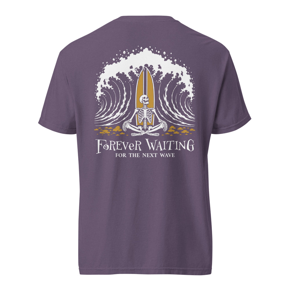 "Forever Waiting For The Next Wave" tee, Grape, back view, featuring a meditating skeleton surfer, board planted upright behind him, sitting cross-legged on the shore as breakers roll in on either side – 17th & Surf