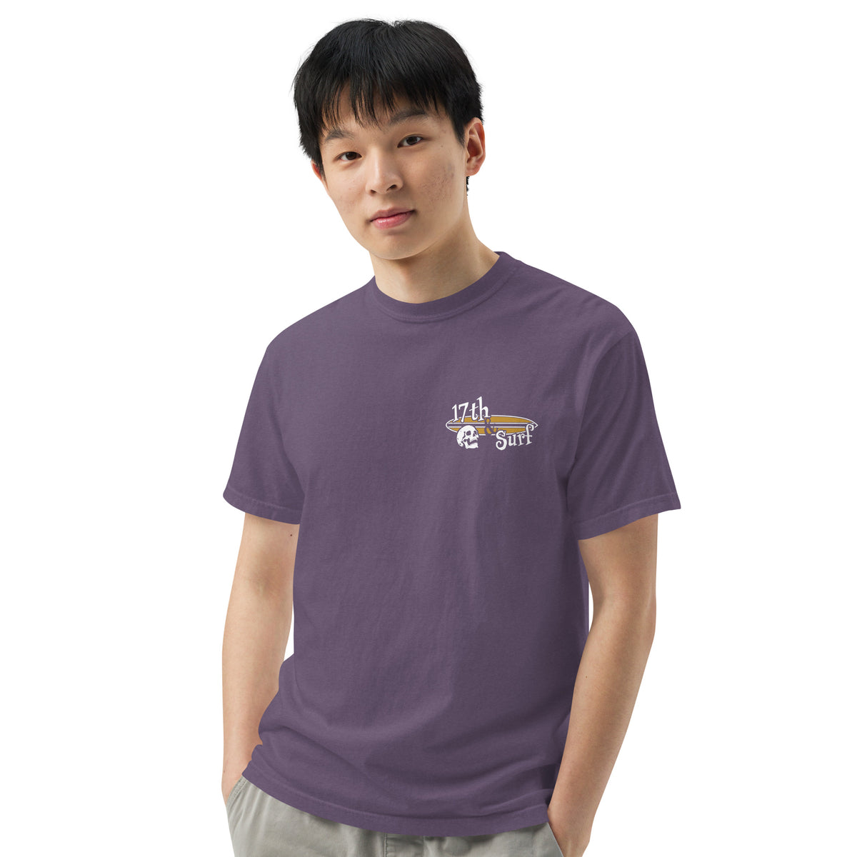 "Forever Waiting For The Next Wave" tee, Grape, third front view, featuring a meditating skeleton surfer, board planted upright behind him, sitting cross-legged on the shore as breakers roll in on either side – 17th & Surf