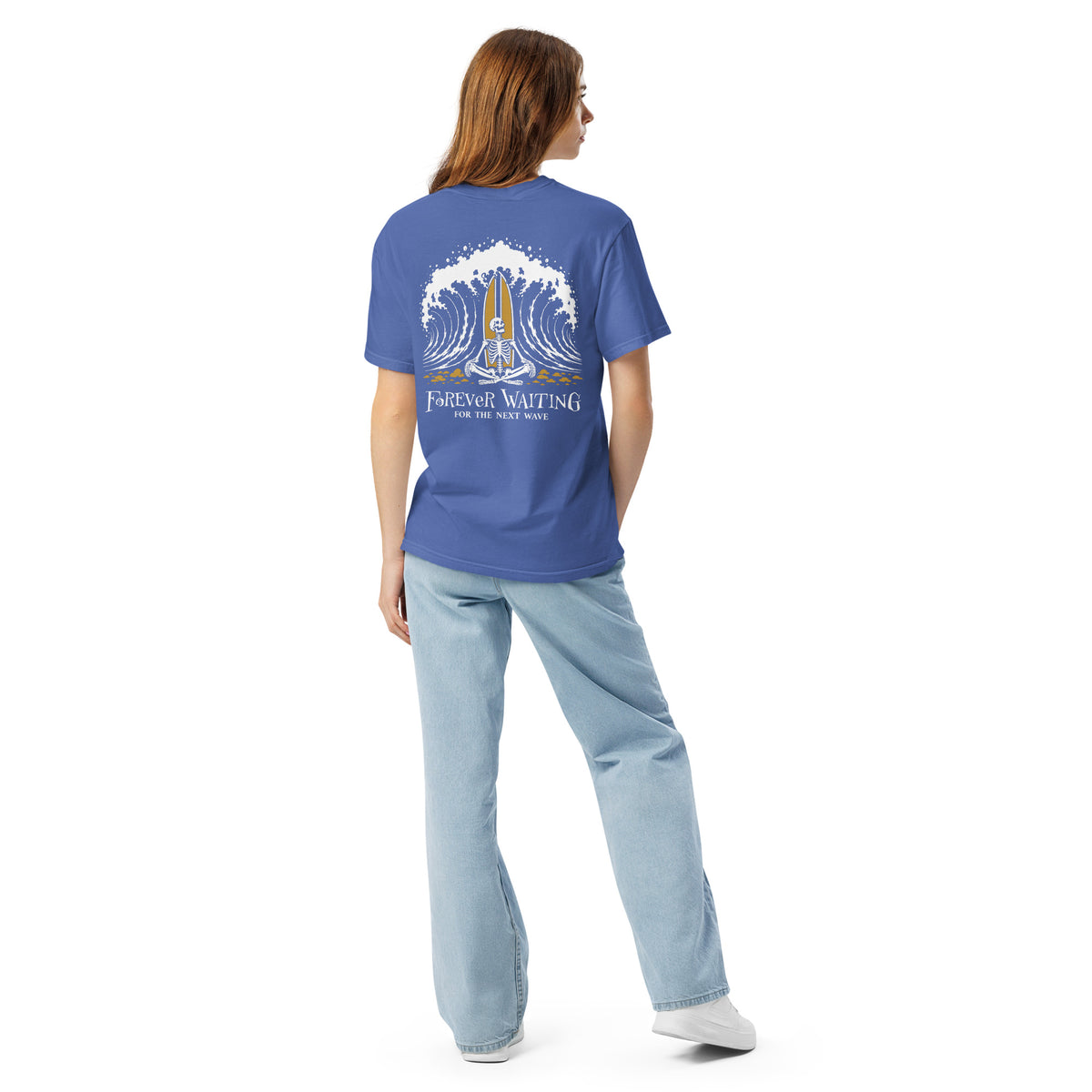 "Forever Waiting For The Next Wave" tee, Mystic Blue, second back view, featuring a meditating skeleton surfer, board planted upright behind him, sitting cross-legged on the shore as breakers roll in on either side – 17th & Surf