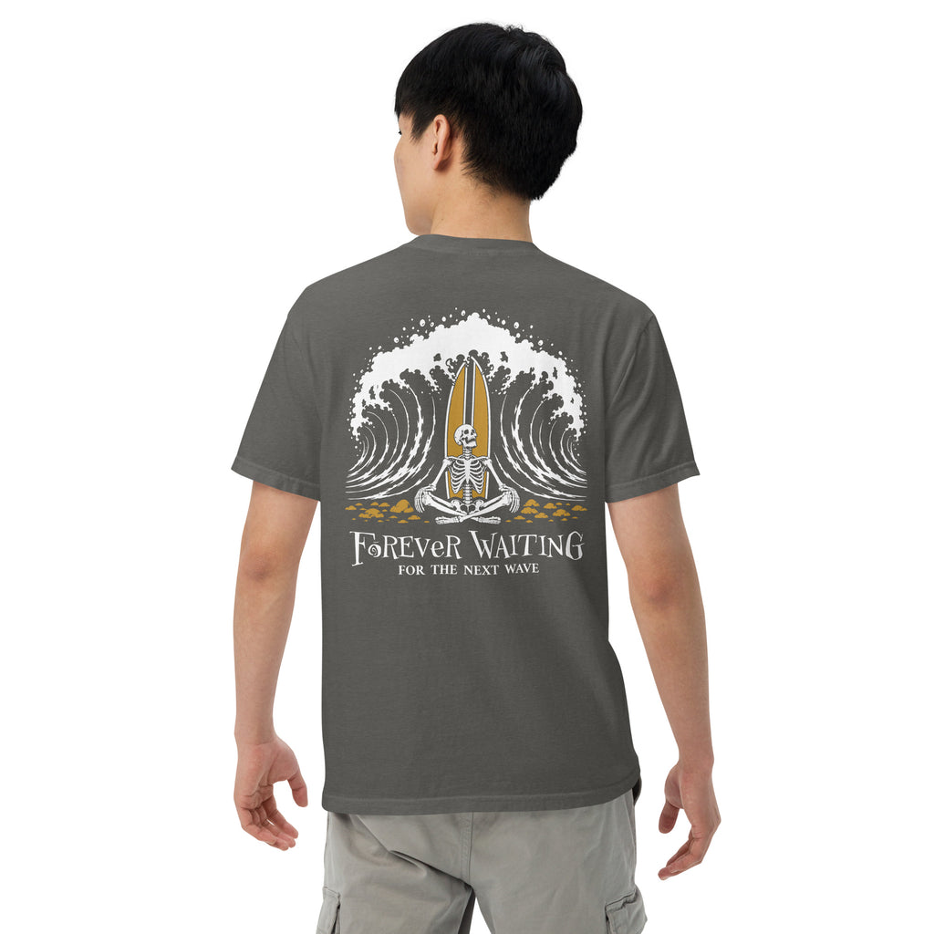 "Forever Waiting For The Next Wave" tee, Pepper, fourth back view, featuring a meditating skeleton surfer, board planted upright behind him, sitting cross-legged on the shore as breakers roll in on either side – 17th & Surf