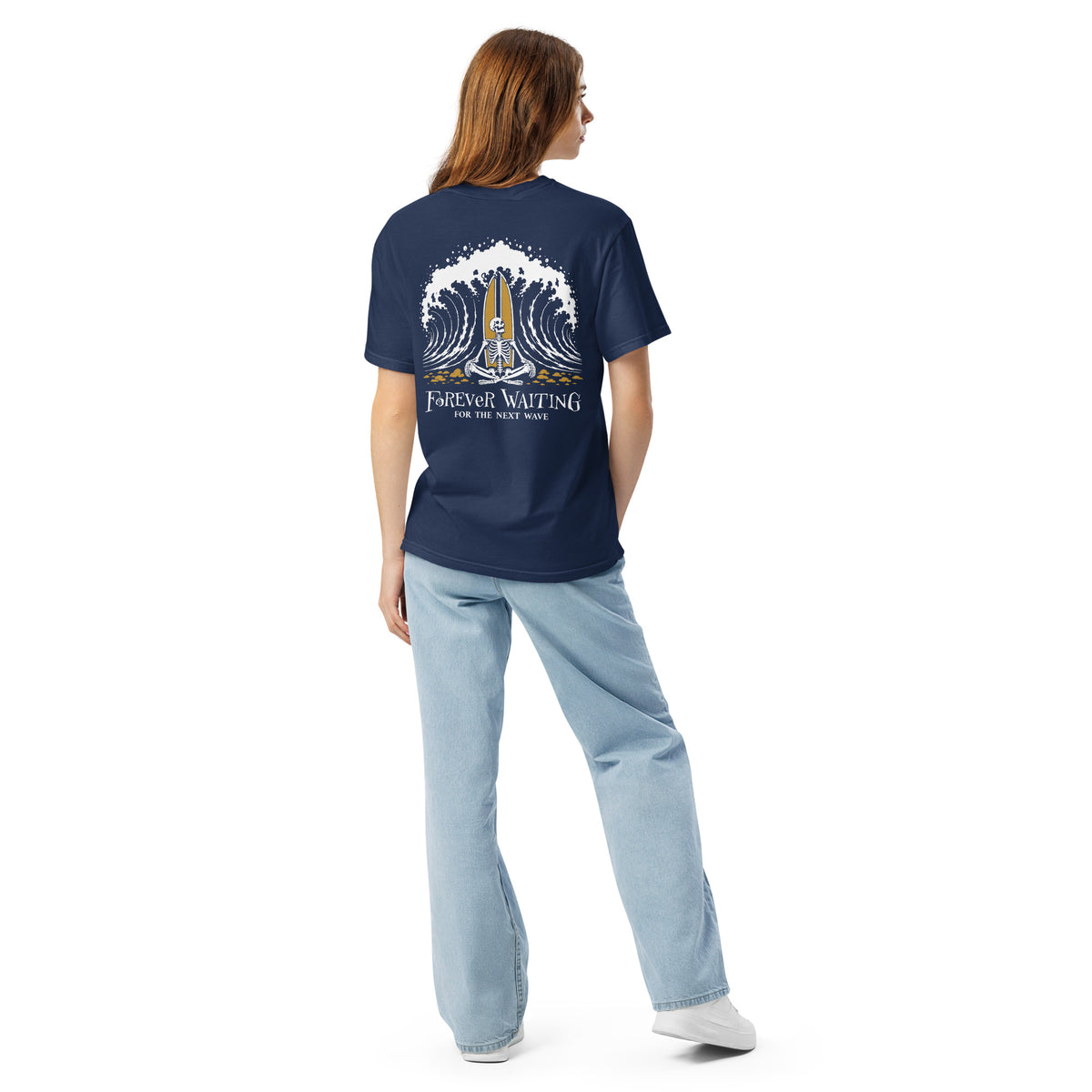 "Forever Waiting For The Next Wave" tee, True Navy, second back view, featuring a meditating skeleton surfer, board planted upright behind him, sitting cross-legged on the shore as breakers roll in on either side – 17th & Surf