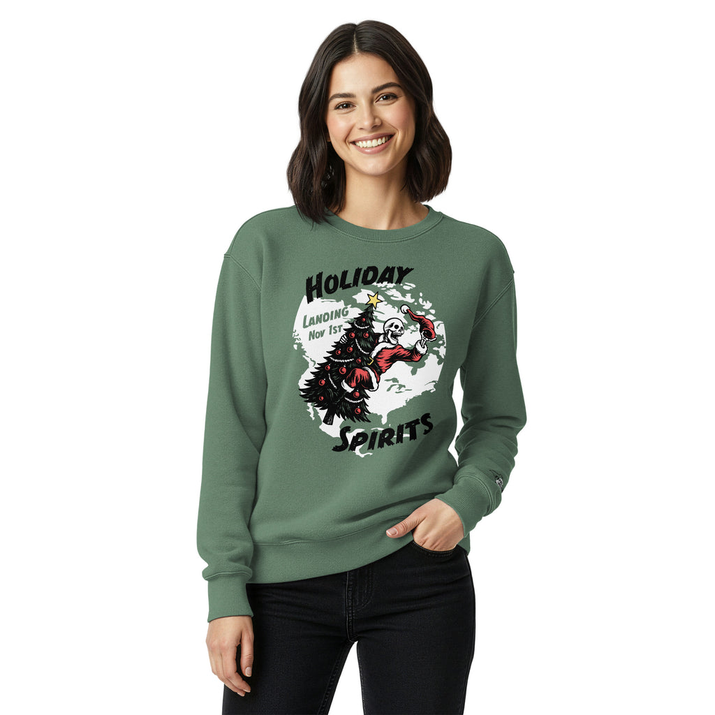 Model wearing "Holiday Spirits" heavyweight crewneck sweatshirt in light green, second front view featuring full color graphic of a skeleton Santa riding a decorated Christmas tree inside a white splatter map shape with arched "Holiday" and "Spirits" text and "Landing Nov 1st" – 17th & Surf