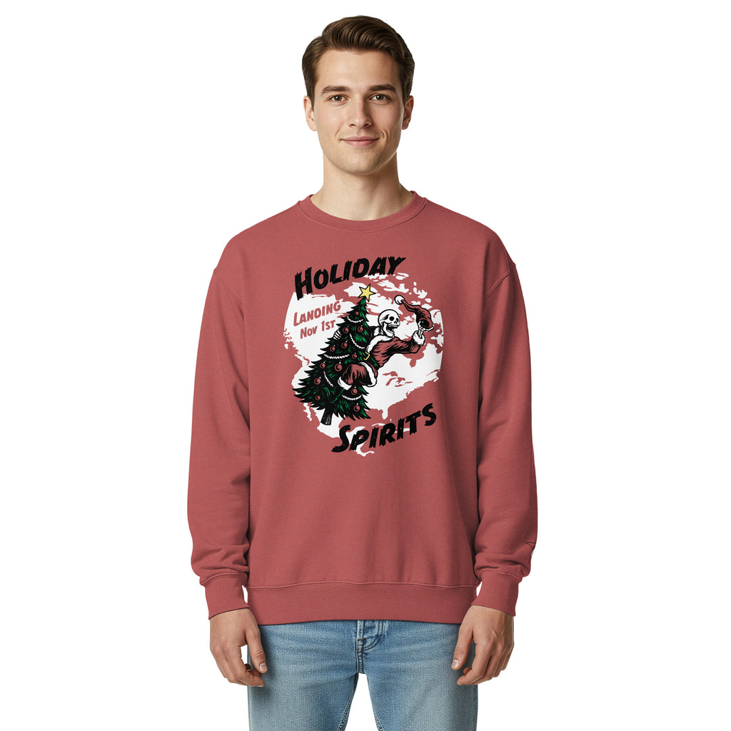 Model wearing "Holiday Spirits" heavyweight crewneck sweatshirt in crimson red, third front view featuring full color graphic of a skeleton Santa riding a decorated Christmas tree inside a white splatter map shape with arched "Holiday" and "Spirits" text and "Landing Nov 1st" – 17th & Surf