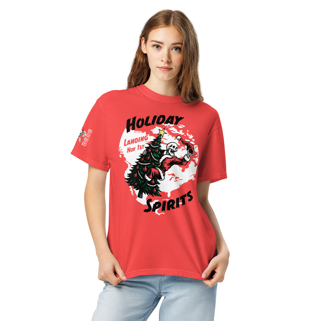 Model wearing "Holiday Spirits" front print garment-dyed heavyweight t-shirt in red, third front view featuring full color graphic of a skeleton Santa riding a decorated Christmas tree inside a white splatter map shape with arched "Holiday" and "Spirits" text and "Landing Nov 1st" – 17th & Surf