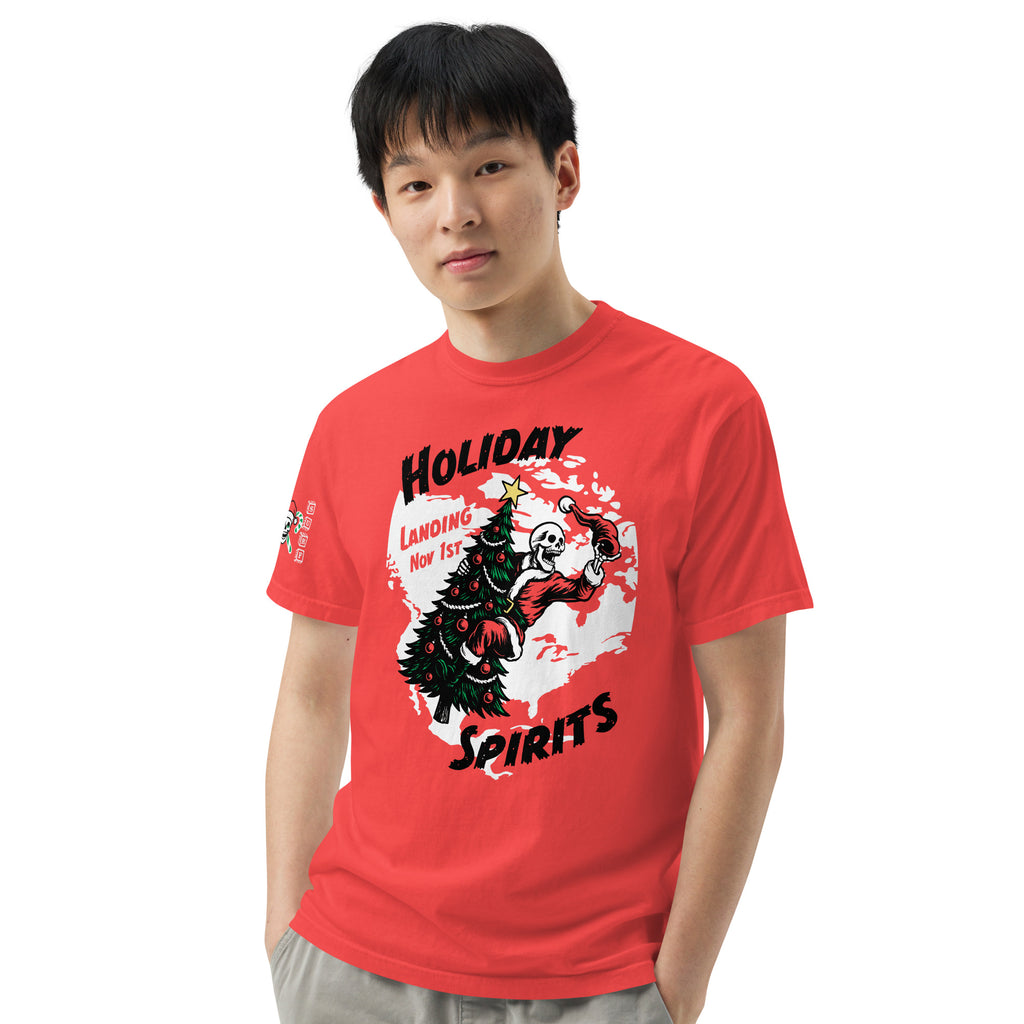 Model wearing "Holiday Spirits" front print garment-dyed heavyweight t-shirt in red, fourth front view featuring full color graphic of a skeleton Santa riding a decorated Christmas tree inside a white splatter map shape with arched "Holiday" and "Spirits" text and "Landing Nov 1st" – 17th & Surf