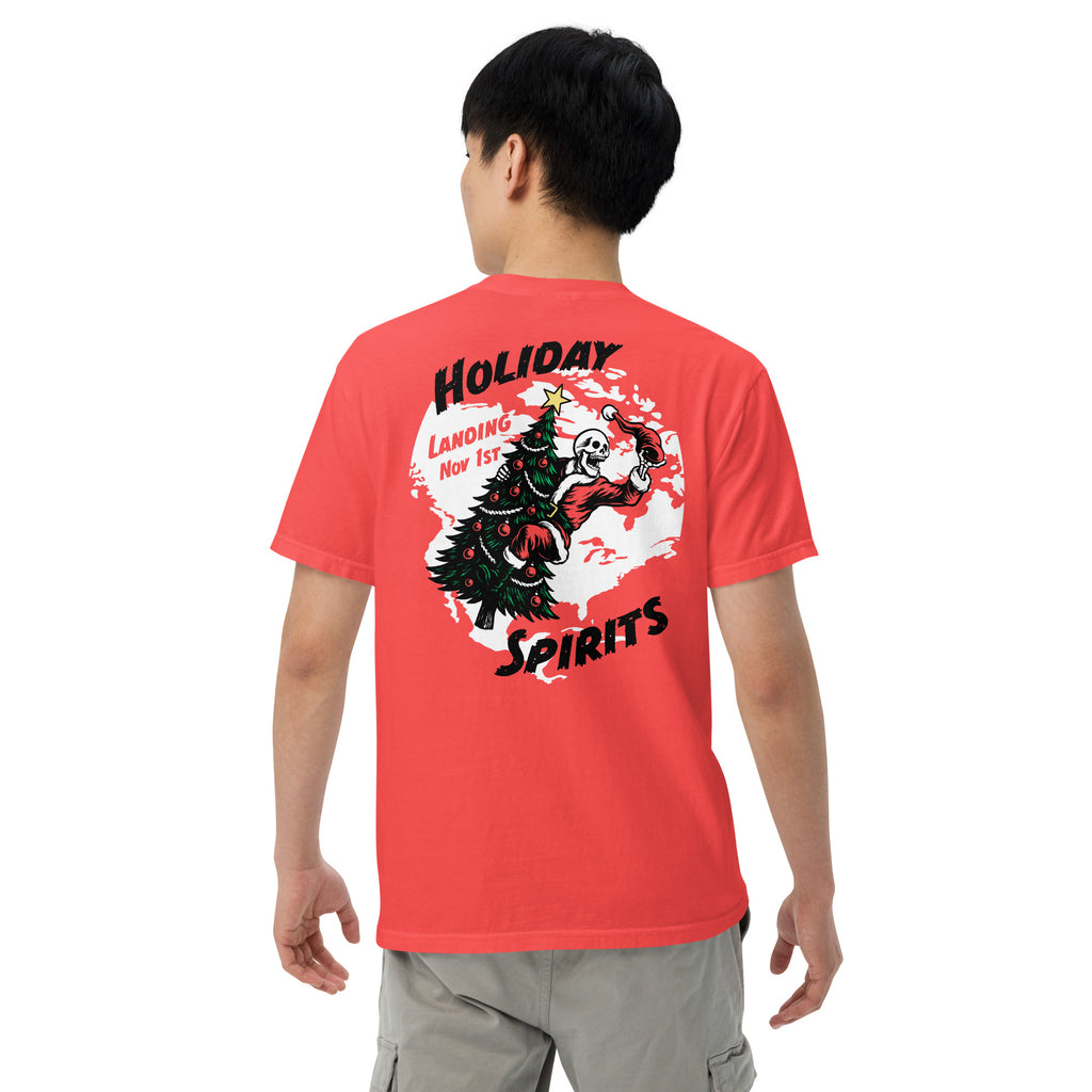 Model wearing "Holiday Spirits" garment-dyed heavyweight t-shirt in red, second back angle view featuring full color graphic of a skeleton Santa riding a decorated Christmas tree inside a white splatter map shape with arched "Holiday" and "Spirits" text and "Landing Nov 1st" – 17th & Surf
