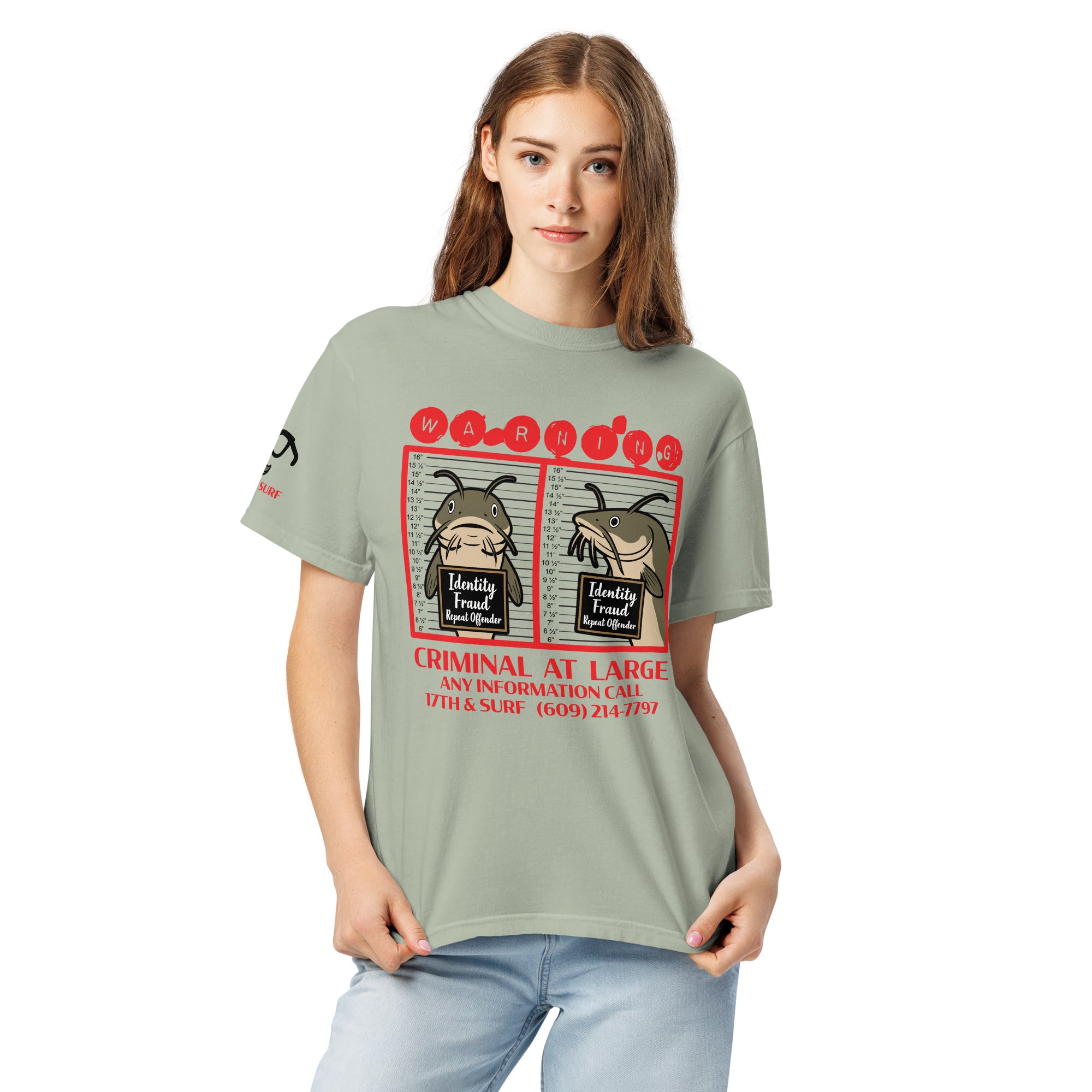 "Identity Fraud" bay garment-dyed heavyweight tee on female model, front view, featuring catfish "WARNING" mugshot graphic with "Identity Fraud, Repeat Offender" police lineup – 17th & Surf
