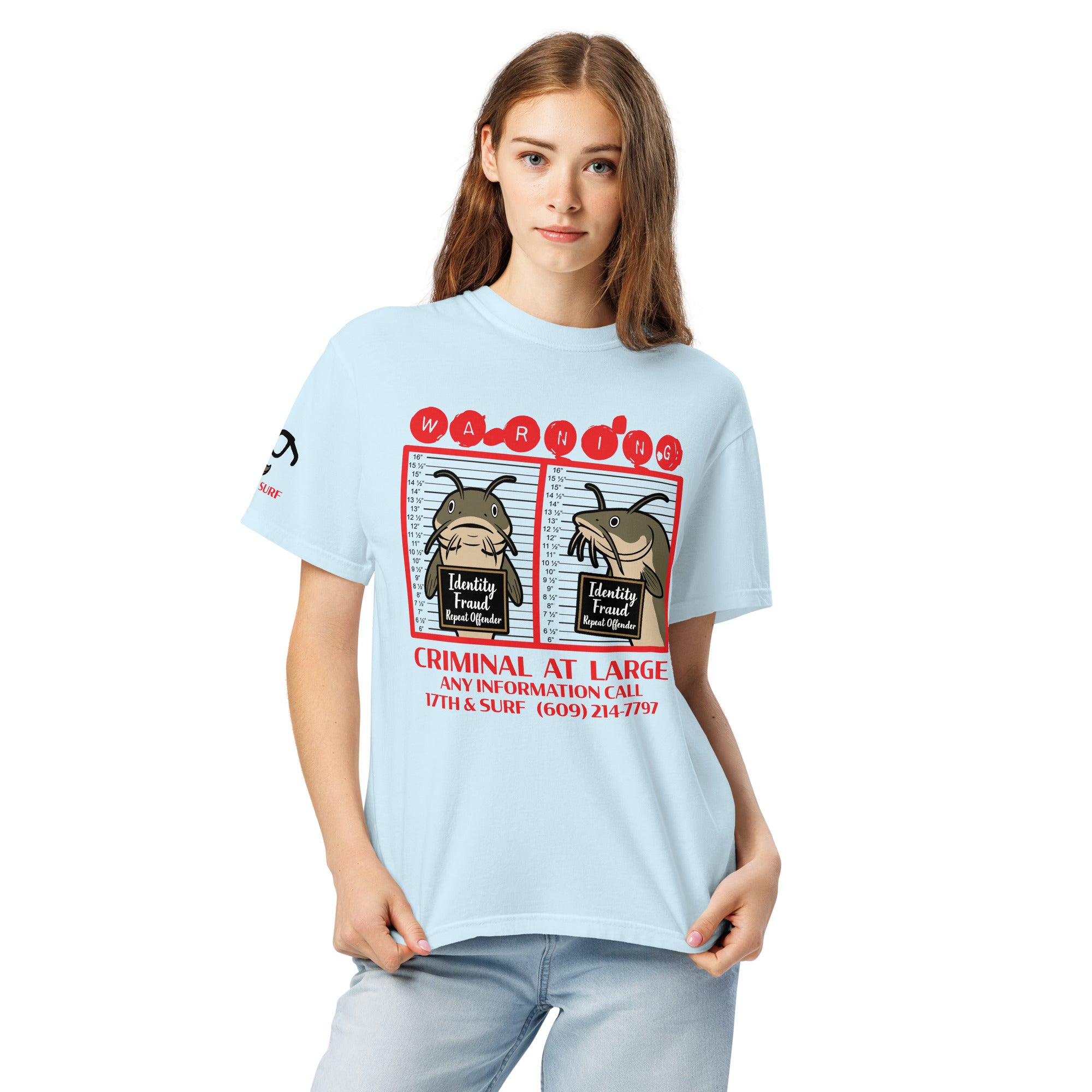 "Identity Fraud" chambray garment-dyed heavyweight tee on female model, front view, featuring catfish "WARNING" mugshot graphic with "Identity Fraud, Repeat Offender" police lineup – 17th & Surf