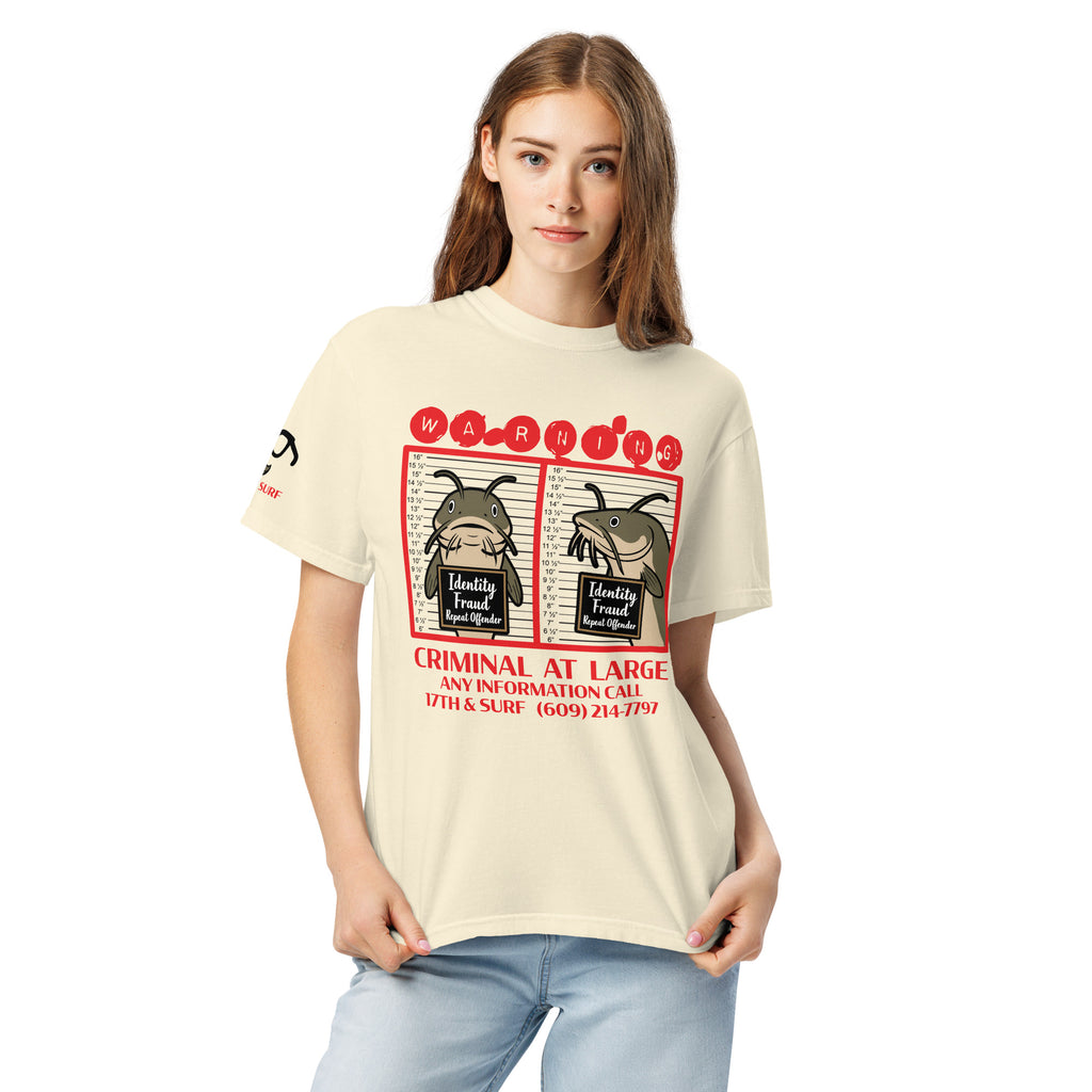 "Identity Fraud" ivory garment-dyed heavyweight tee on female model, front view, featuring catfish "WARNING" mugshot graphic with "Identity Fraud, Repeat Offender" police lineup – 17th & Surf