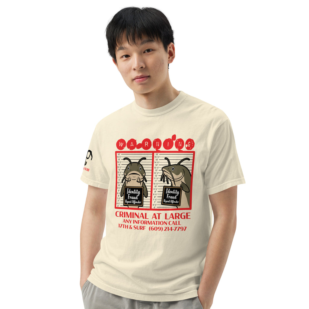 "Identity Fraud" ivory garment-dyed heavyweight tee on male model, front view, featuring catfish "WARNING" mugshot graphic with "Identity Fraud, Repeat Offender" police lineup – 17th & Surf