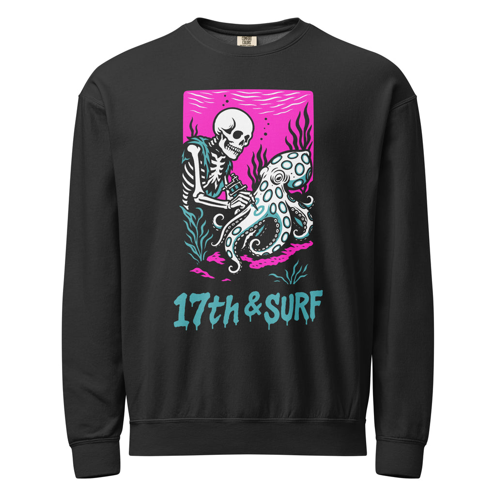 "Inked" garment-dyed lightweight crewneck sweatshirt front view in black featuring skeleton tattooing an octopus graphic with "17th & Surf" text on pink background – 17th & Surf
