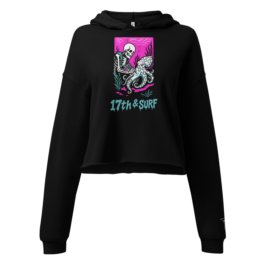 "Inked" cropped hoodie front flat lay in black featuring skeleton tattooing an octopus graphic with "17th & Surf" text on pink background – 17th & Surf