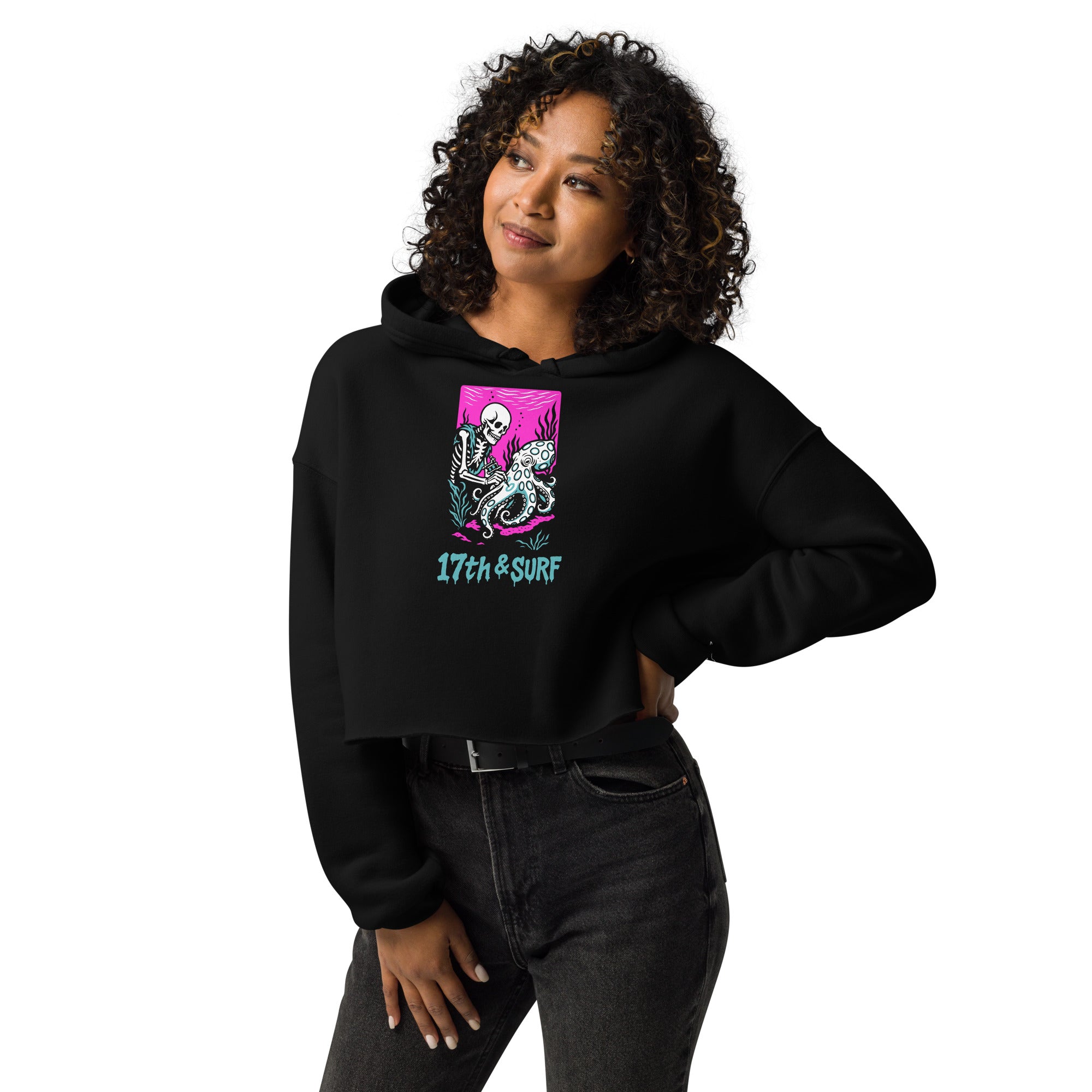 "Inked" cropped hoodie front view on model in black featuring skeleton tattooing an octopus graphic with "17th & Surf" text on pink background – 17th & Surf