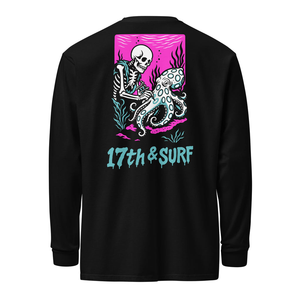"Inked" garment-dyed heavyweight long sleeve back flat lay in black featuring skeleton tattooing an octopus graphic with "17th & Surf" text on pink background – 17th & Surf