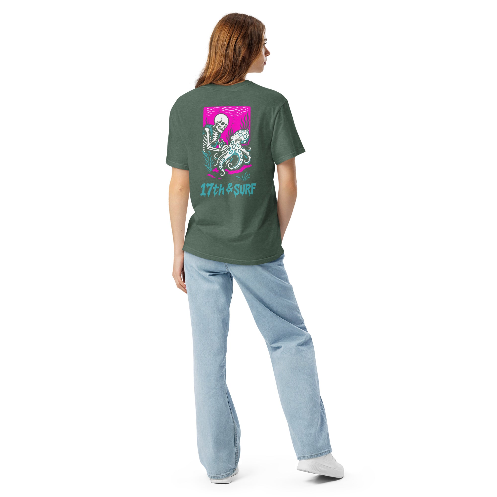 "Inked" garment-dyed heavyweight tee back view in blue spruce featuring skeleton tattooing an octopus graphic with "17th & Surf" text on pink background – 17th & Surf
