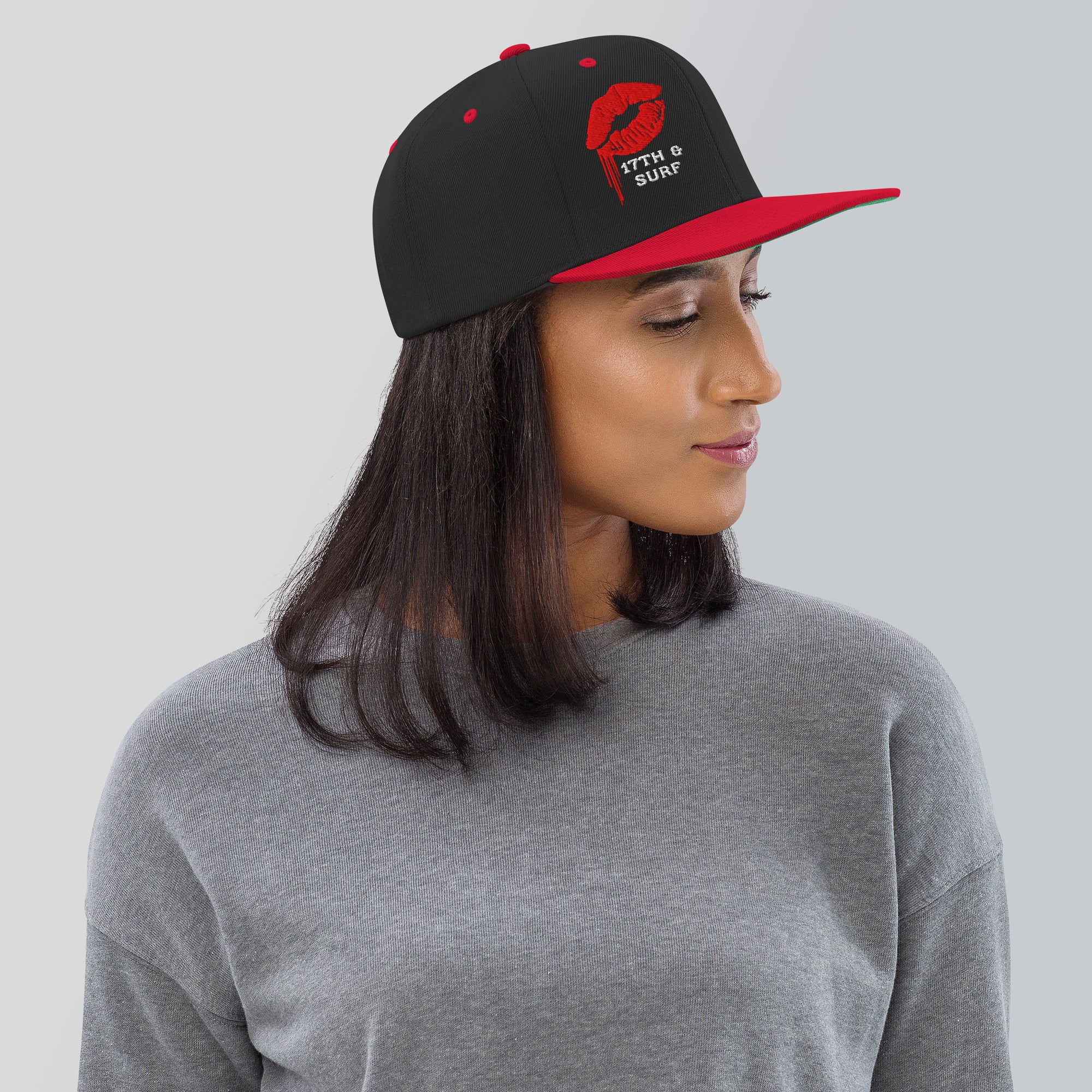 Model wearing the 17th & Surf Kiss snapback hat, black and red with a red dripping lips graphic and "17TH & SURF" text – 17th & Surf