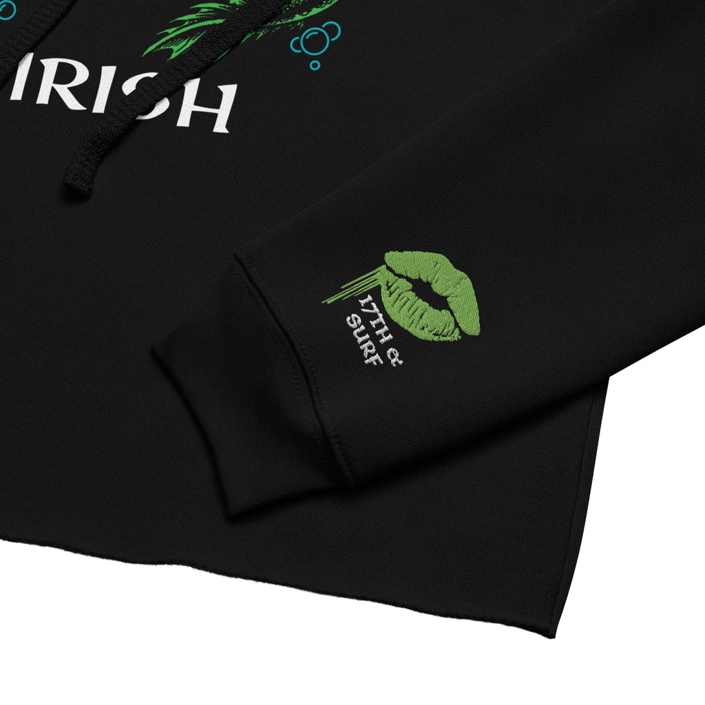 "Kiss Me I'm Irish" Anglerfish black cropped hoodie close-up detail, showing the "IRISH" text corner of the anglerfish design and the green dripping-lips "17TH & SURF" sleeve cuff logo – 17th & Surf