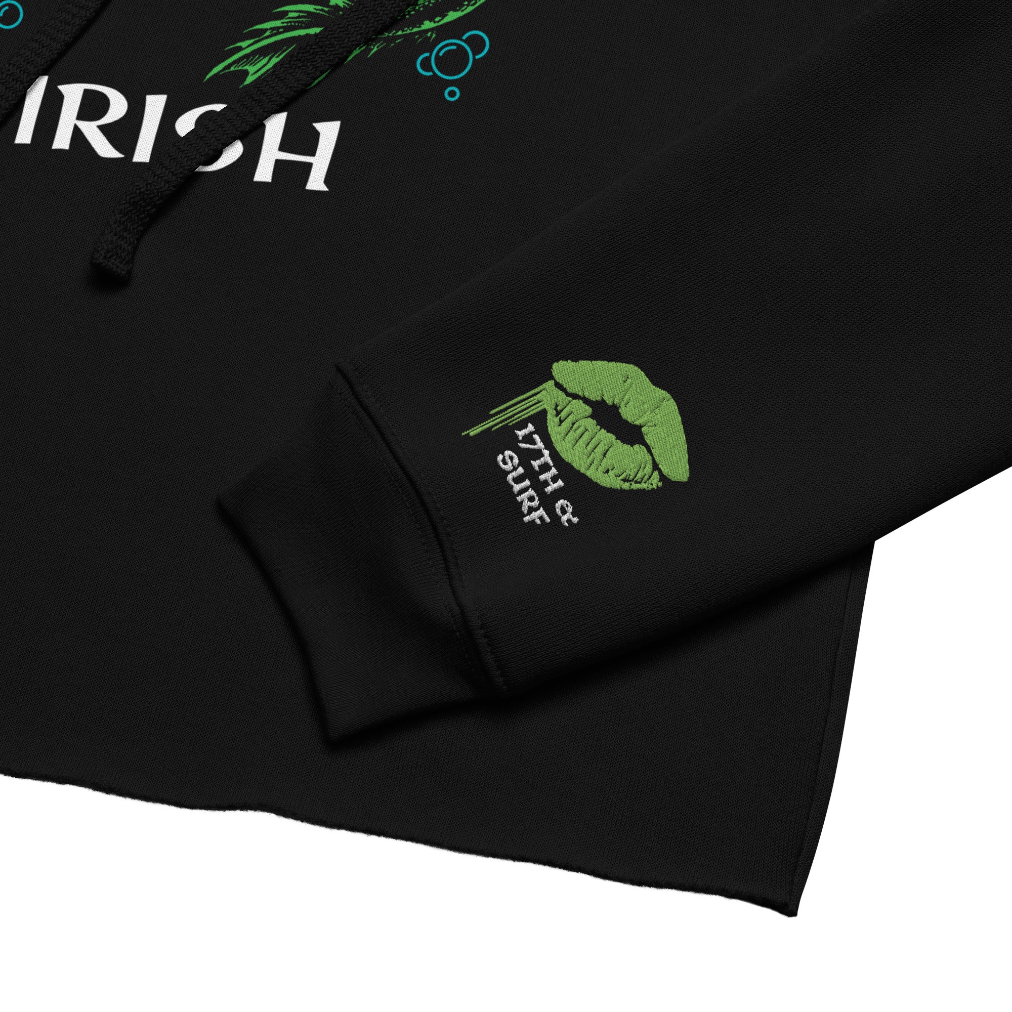 "Kiss Me I'm Irish" Anglerfish black cropped hoodie close-up detail, showing the "IRISH" text corner of the anglerfish design and the green dripping-lips "17TH & SURF" sleeve cuff logo – 17th & Surf