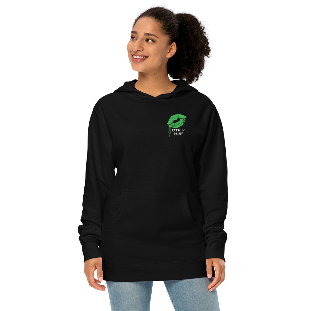 "Kiss Me I'm Irish" Anglerfish black midweight hoodie on female model, front view, featuring a green dripping-lips "17TH & SURF" logo on the chest – 17th & Surf