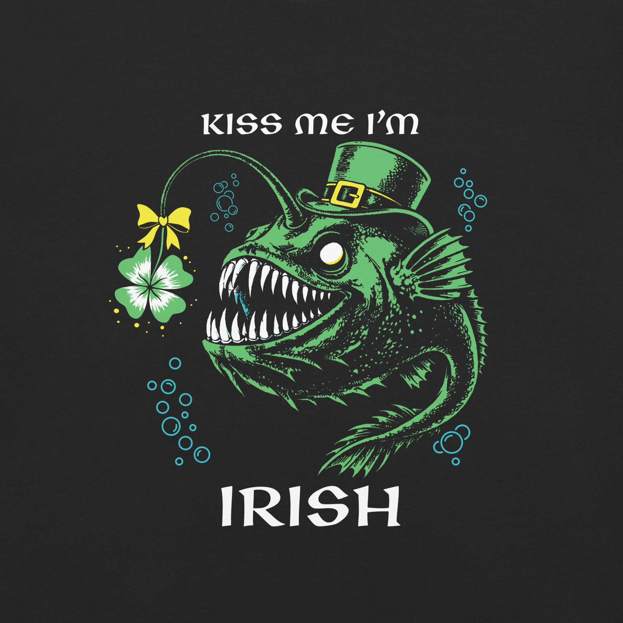 "Kiss Me I'm Irish" Anglerfish design close-up, featuring a green anglerfish wearing a leprechaun top hat with a yellow-bowed shamrock lure, sharp teeth, and teal bubble accents alongside "KISS ME I'M IRISH" text – 17th & Surf