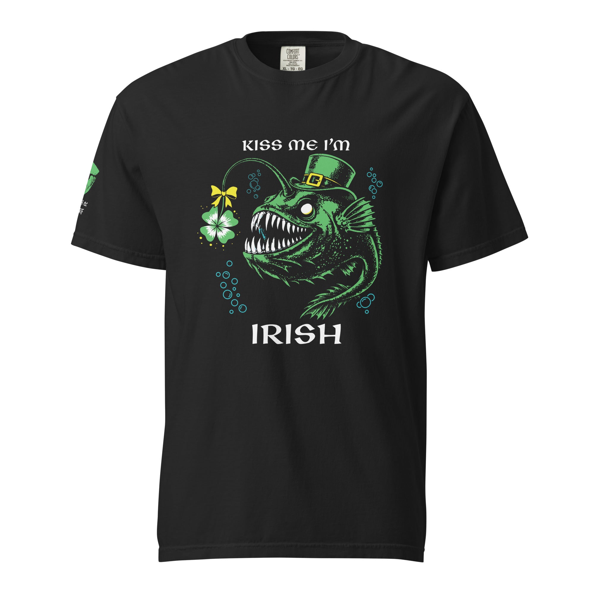 "Kiss Me I'm Irish" Anglerfish black tee, front flat lay, featuring a green anglerfish in a leprechaun hat with a shamrock lure and "KISS ME I'M IRISH" text, plus a green dripping-lips "17TH & SURF" logo on the sleeve – 17th & Surf