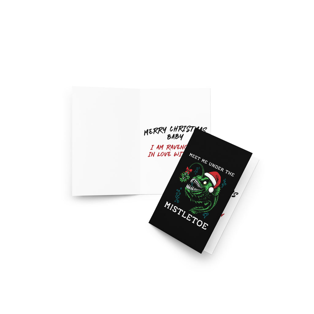 "Mistletoe" Anglerfish 4x6 greeting card, lifestyle flat lay showing the open card with "Merry Christmas Baby" interior message and anglerfish front cover – 17th & Surf