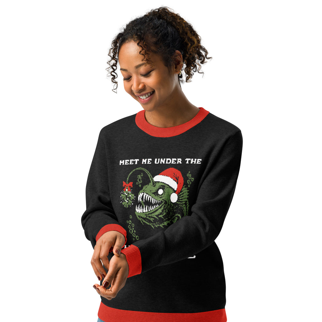 "Mistletoe" Anglerfish charcoal knitted Christmas sweater with red ribbed trim on female model, front view, featuring a green anglerfish wearing a Santa hat with mistletoe and "Meet Me Under The Mistletoe" graphic – 17th & Surf