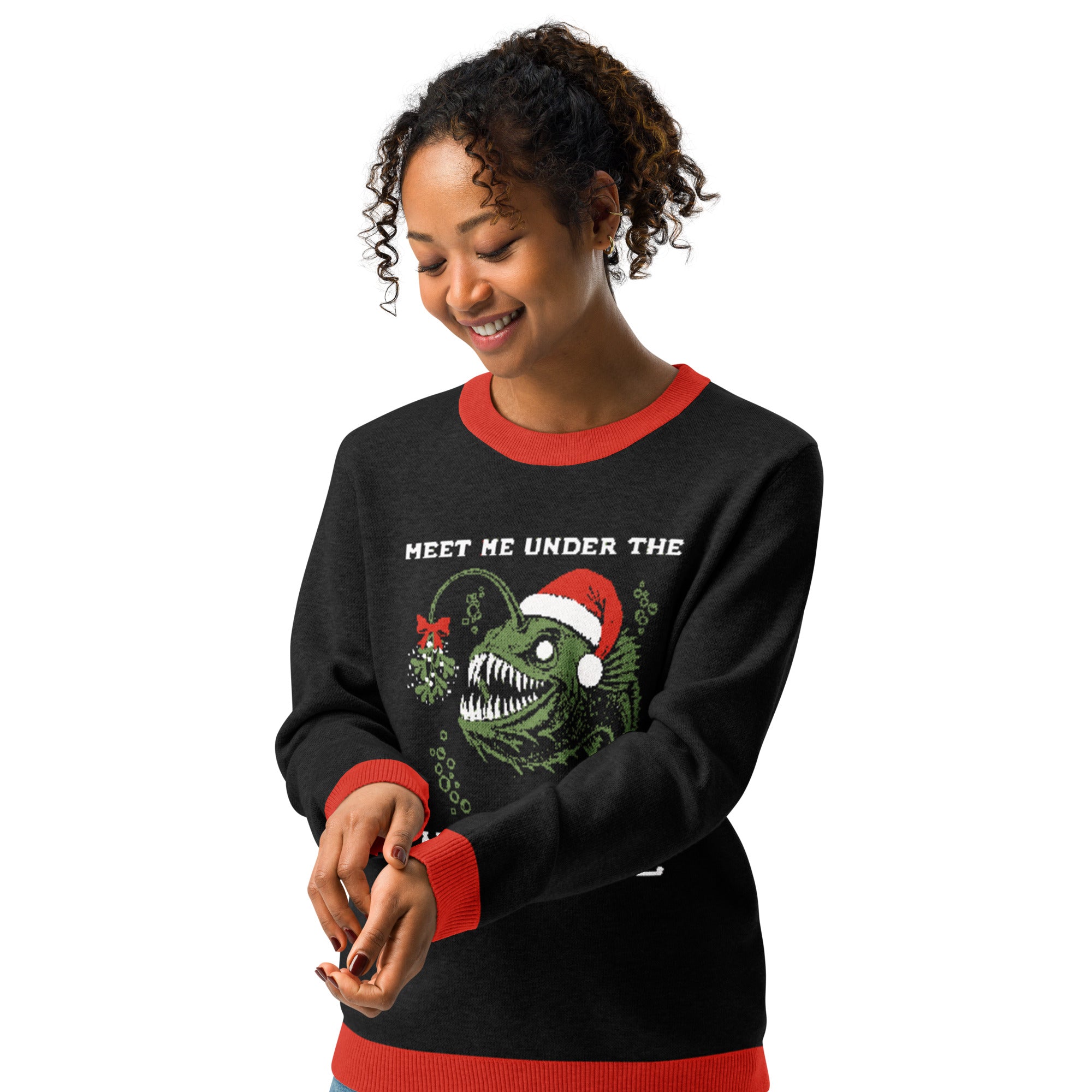 "Mistletoe" Anglerfish charcoal knitted Christmas sweater with red ribbed trim on female model, front view, featuring a green anglerfish wearing a Santa hat with mistletoe and "Meet Me Under The Mistletoe" graphic – 17th & Surf