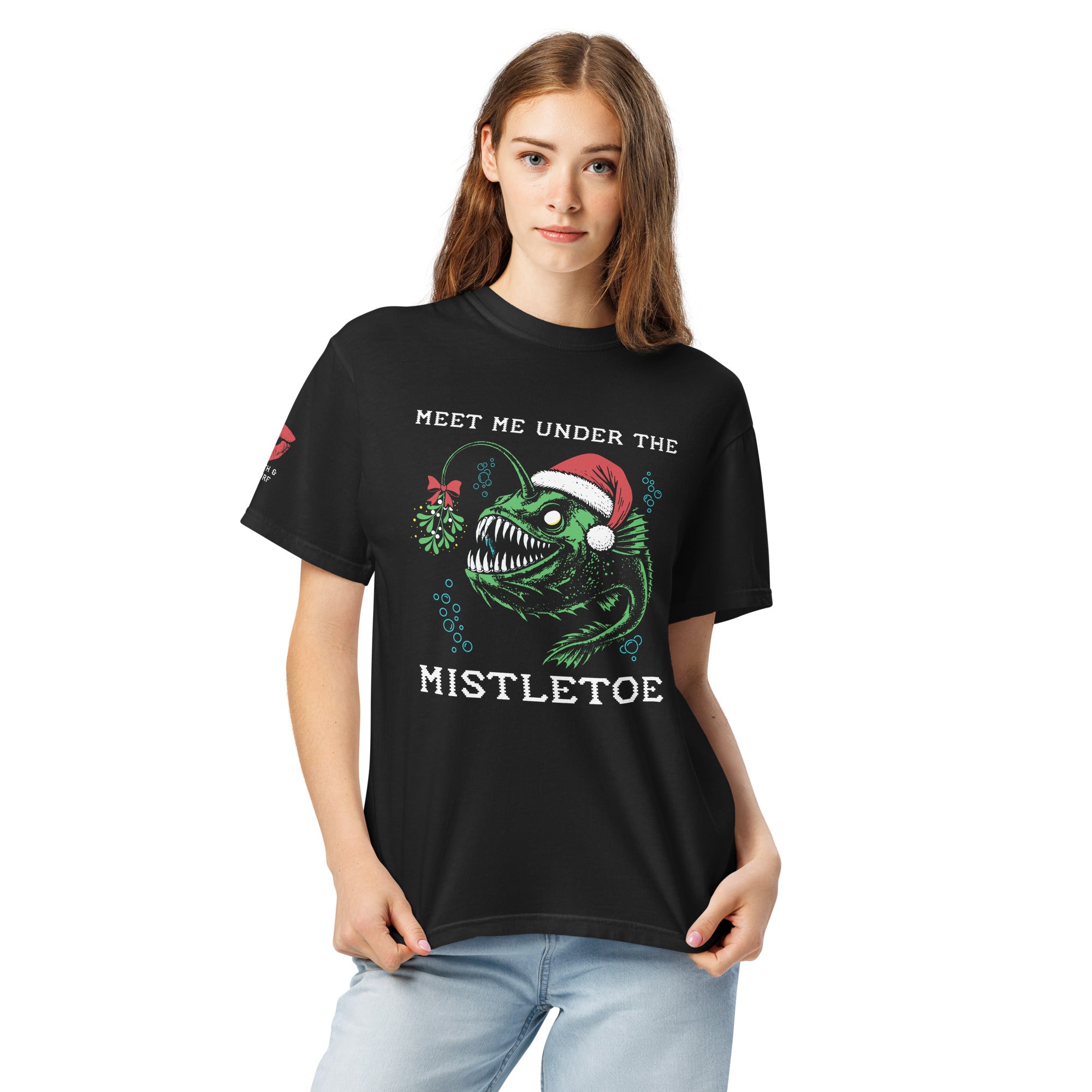 "Mistletoe" Anglerfish black heavyweight t-shirt on female model, front view, featuring a green anglerfish wearing a Santa hat with mistletoe and "Meet Me Under The Mistletoe" graphic – 17th & Surf