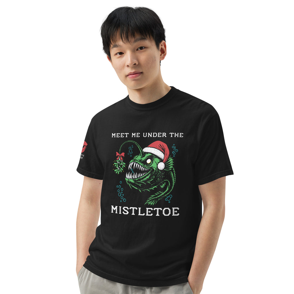 "Mistletoe" Anglerfish black heavyweight t-shirt on male model, front view, featuring a green anglerfish wearing a Santa hat with mistletoe and "Meet Me Under The Mistletoe" graphic – 17th & Surf