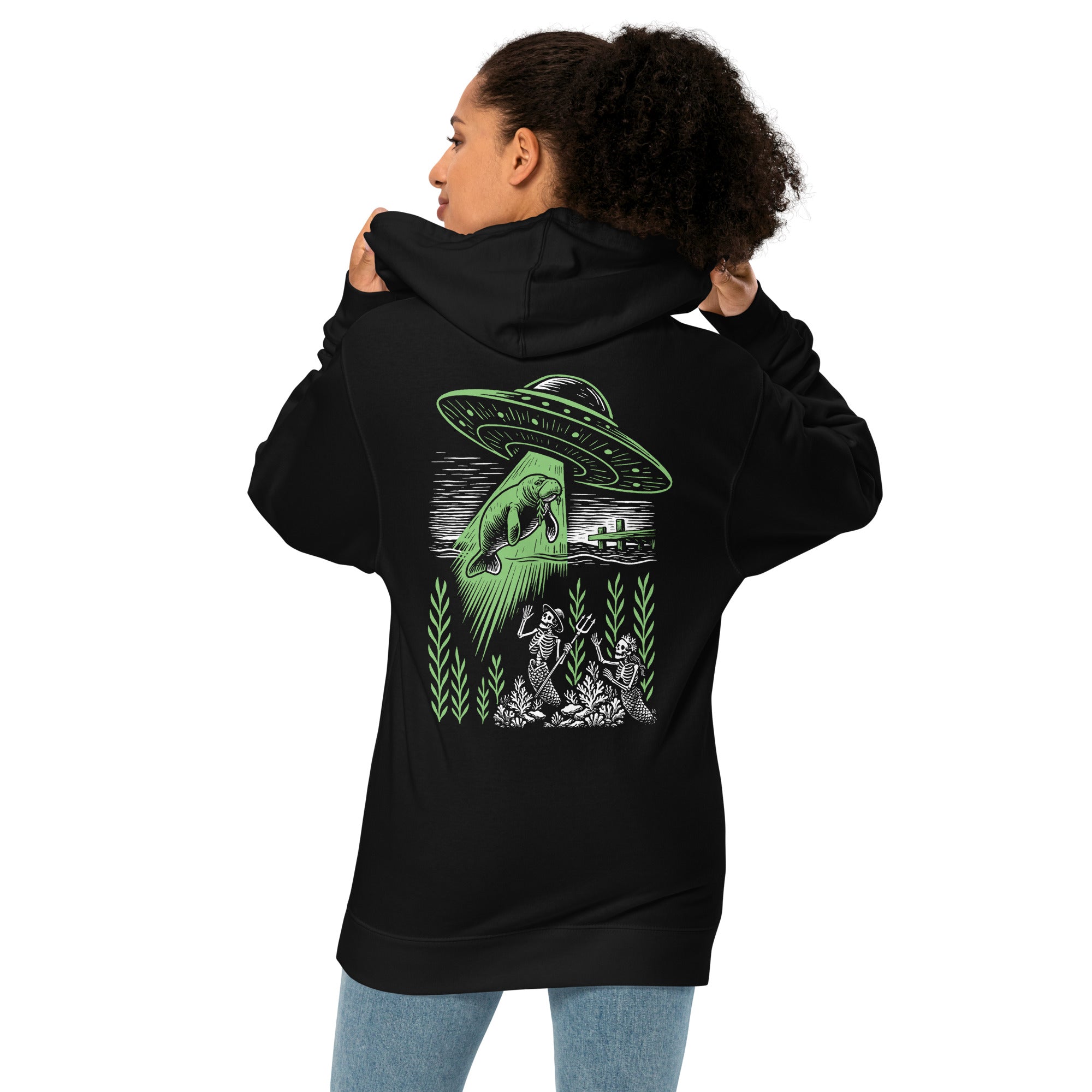 "Ocean Abduction" garment-dyed heavyweight hoodie, female model back view, featuring UFO abducting a manatee via tractor beam over skeleton mermaids design – 17th & Surf